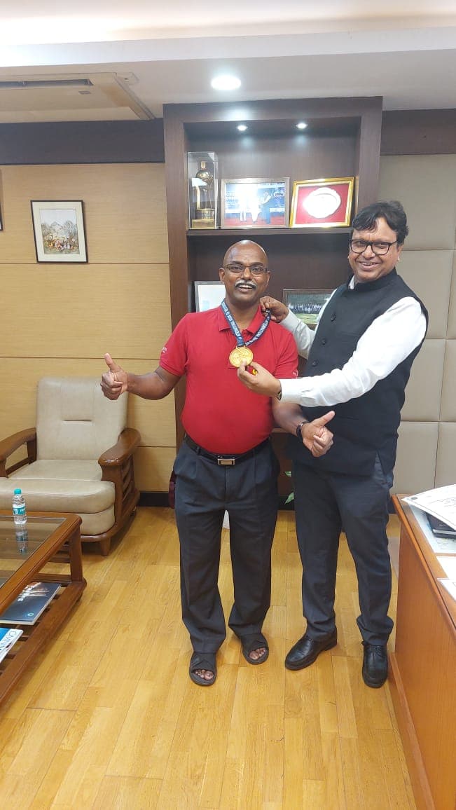 Bobba Ravinder Reddy holding up a medal with a colleague at an office celebration