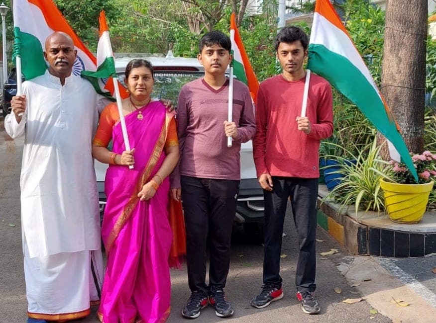 Family of four holding Indian flags together outdoors, Bobba Ravinder Reddy in a white kurta