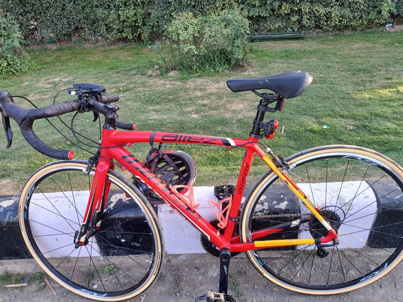 Close-up of Bobba Ravinder Reddy's red Specialized Allez road bicycle parked on a grassy curb