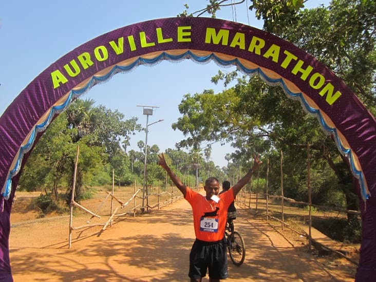 Bobba Ravinder Reddy celebrating under the Auroville Marathon finish arch