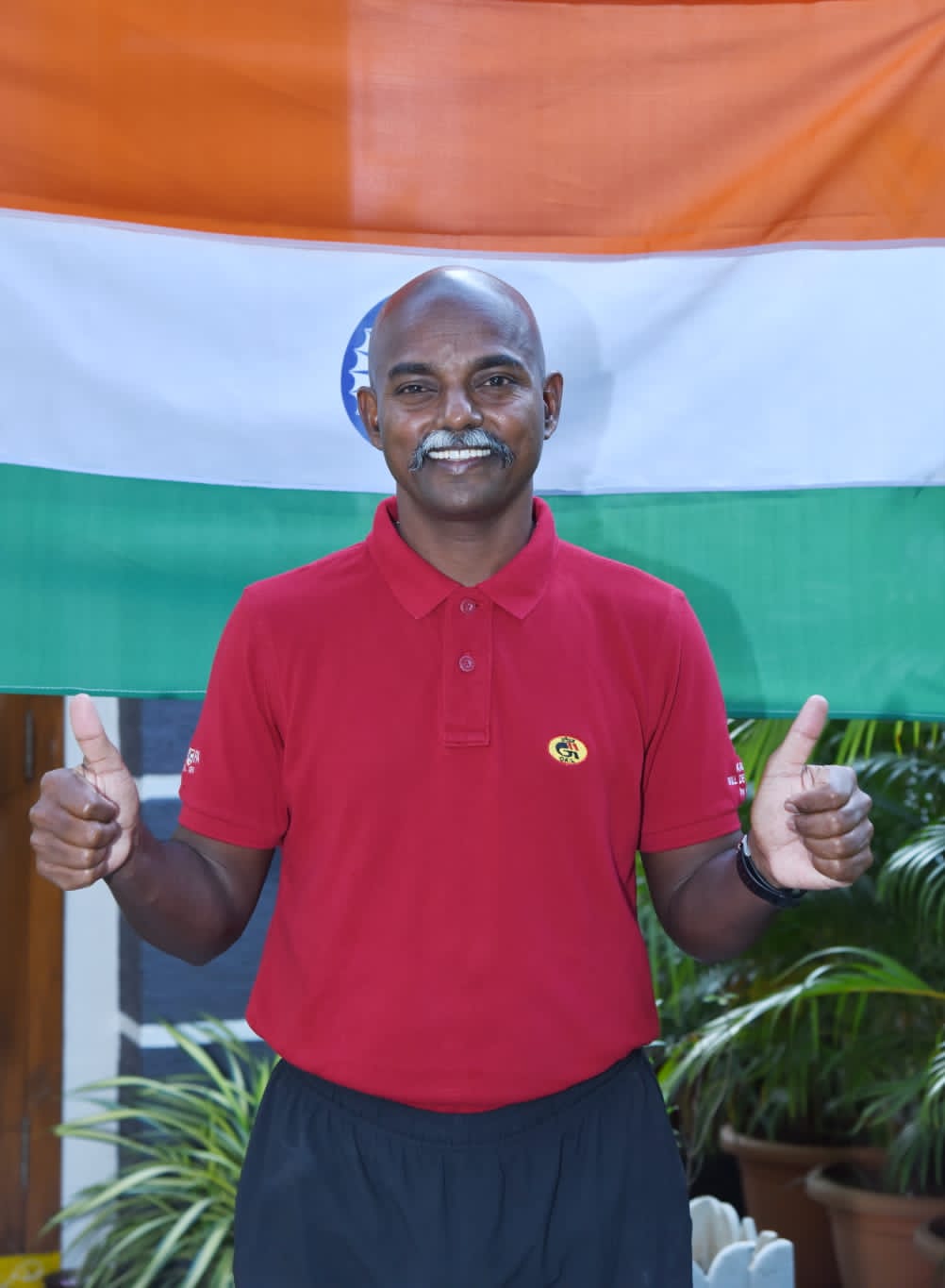 Bobba Ravinder Reddy giving a thumbs up in front of the Indian flag