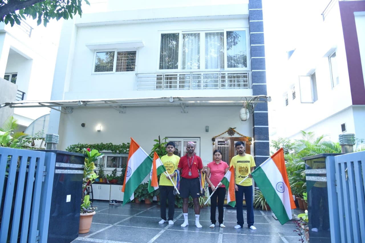 Family group holding Indian flags outside a house gate