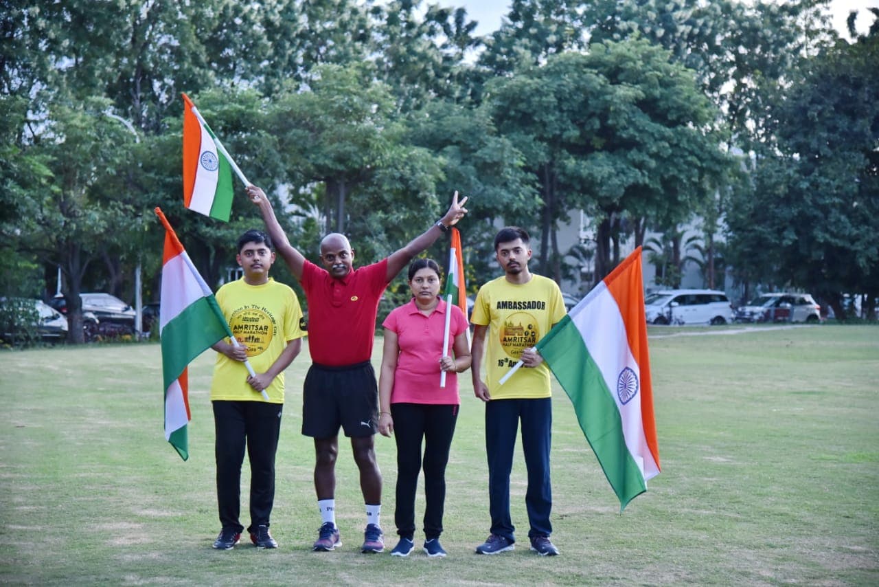 Family group holding Indian flags on a grass field