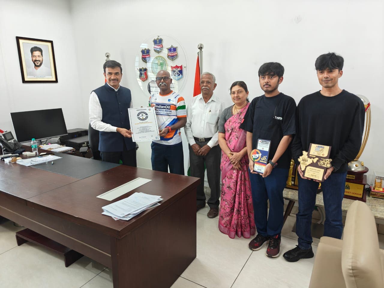Bobba Ravinder Reddy receiving a certificate from an official in a government office, flanked by family and dignitaries