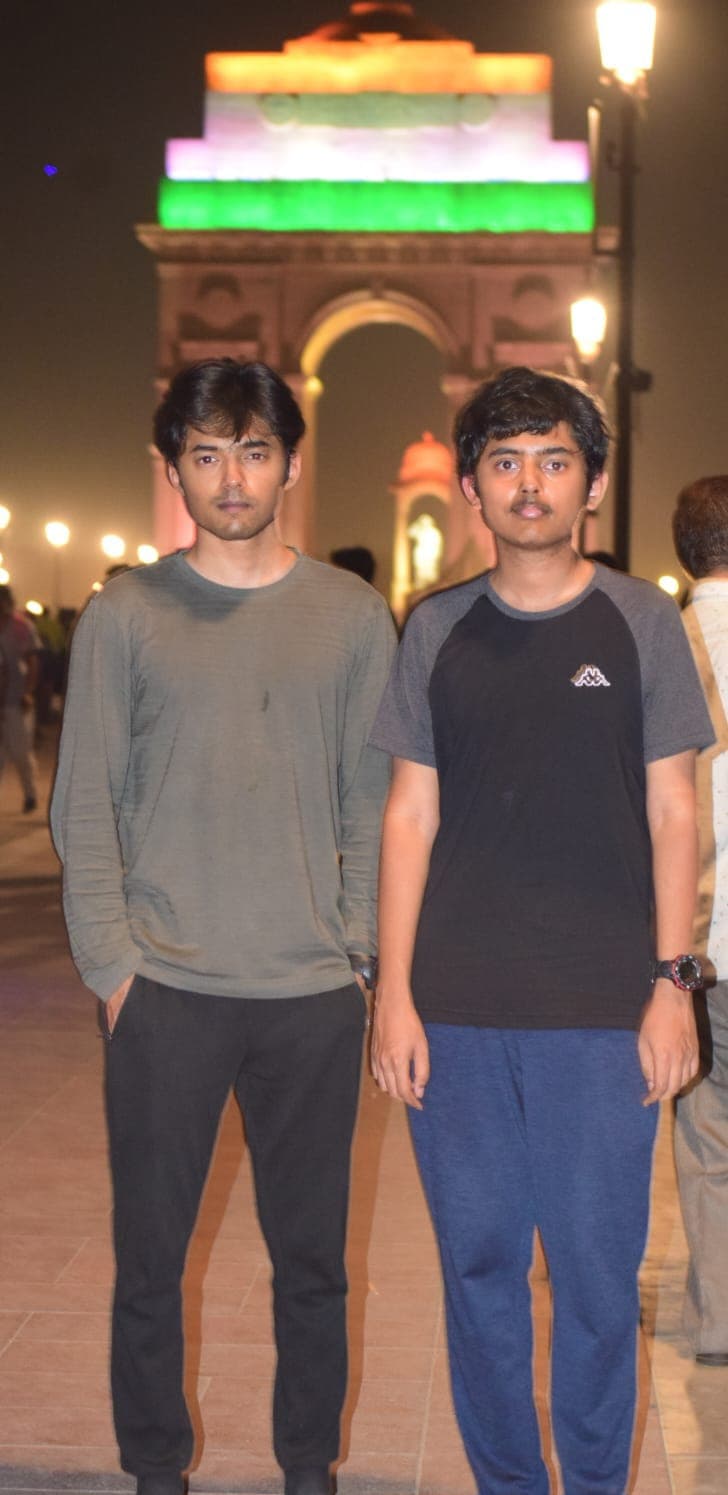 Bobba Gnan Reddy and Bobba Dilip Reddy standing together at India Gate lit up at night, portrait view
