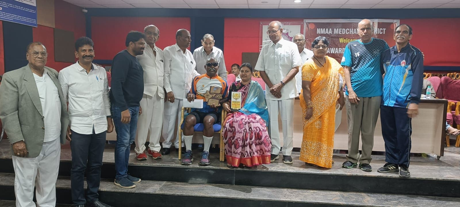 Bobba Ravinder Reddy seated on stage receiving an award at an NMAA Medchal District felicitation event