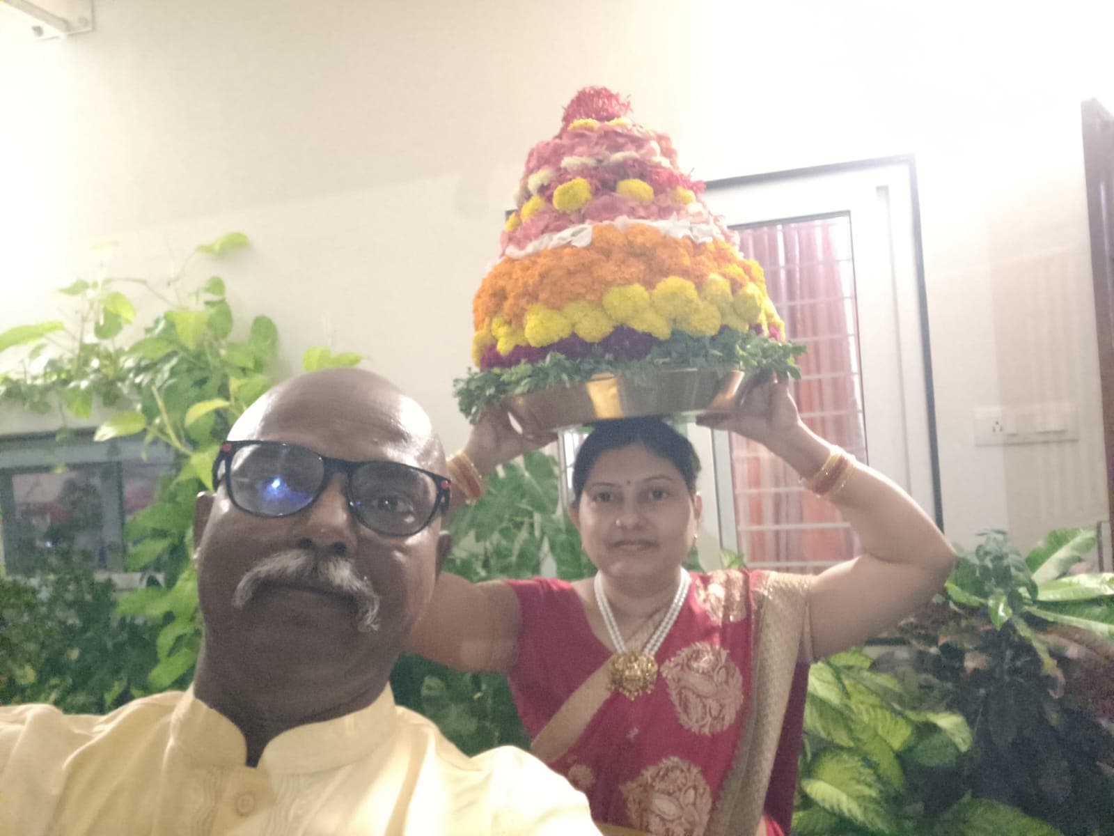 Selfie of Bobba Ravinder Reddy and his wife with an elaborate flower garland offering balanced on her head