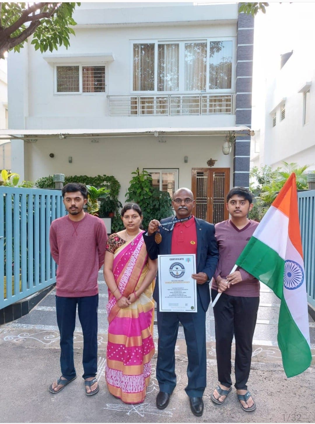 Family of four holding the Indian flag and a world record certificate in front of their house