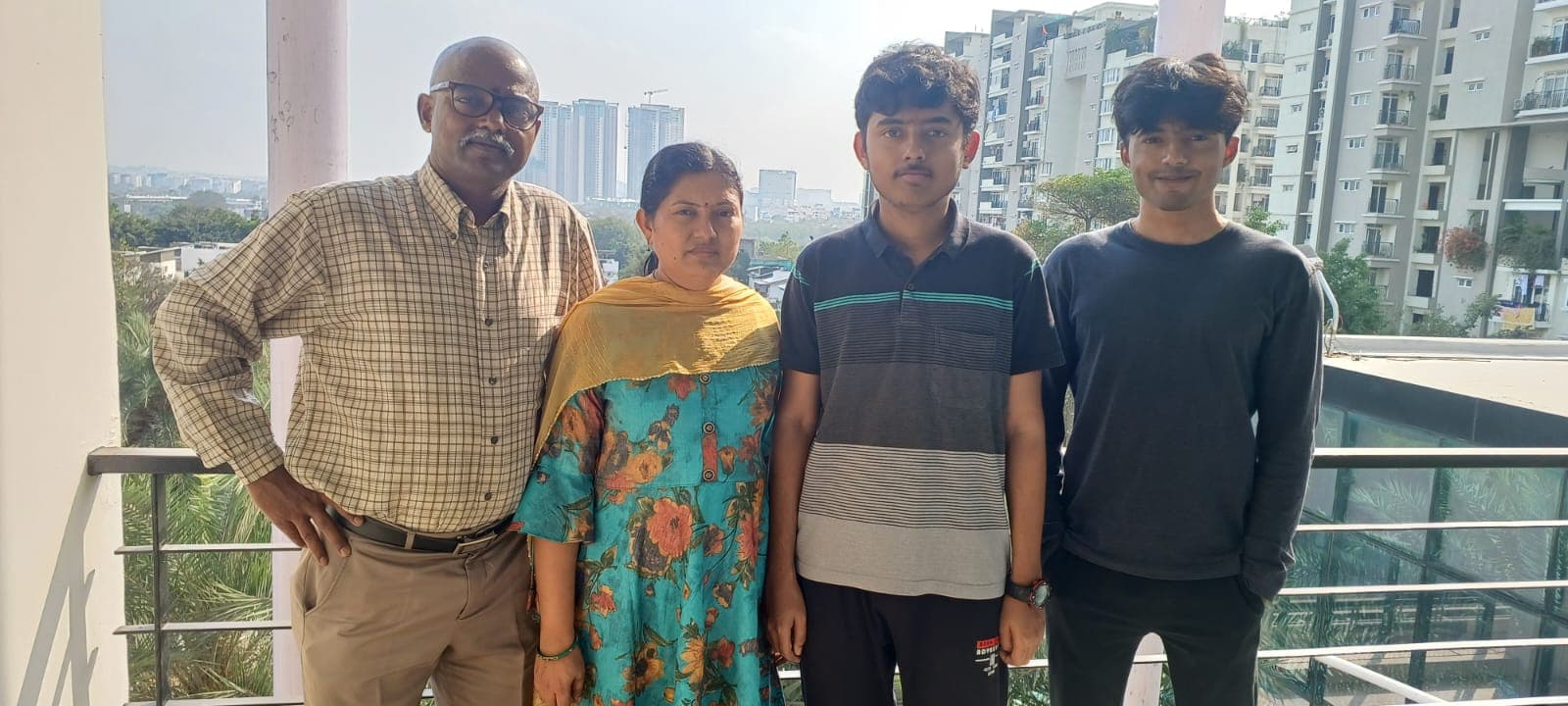 Bobba Ravinder Reddy with his wife and two sons on an apartment balcony overlooking the city skyline