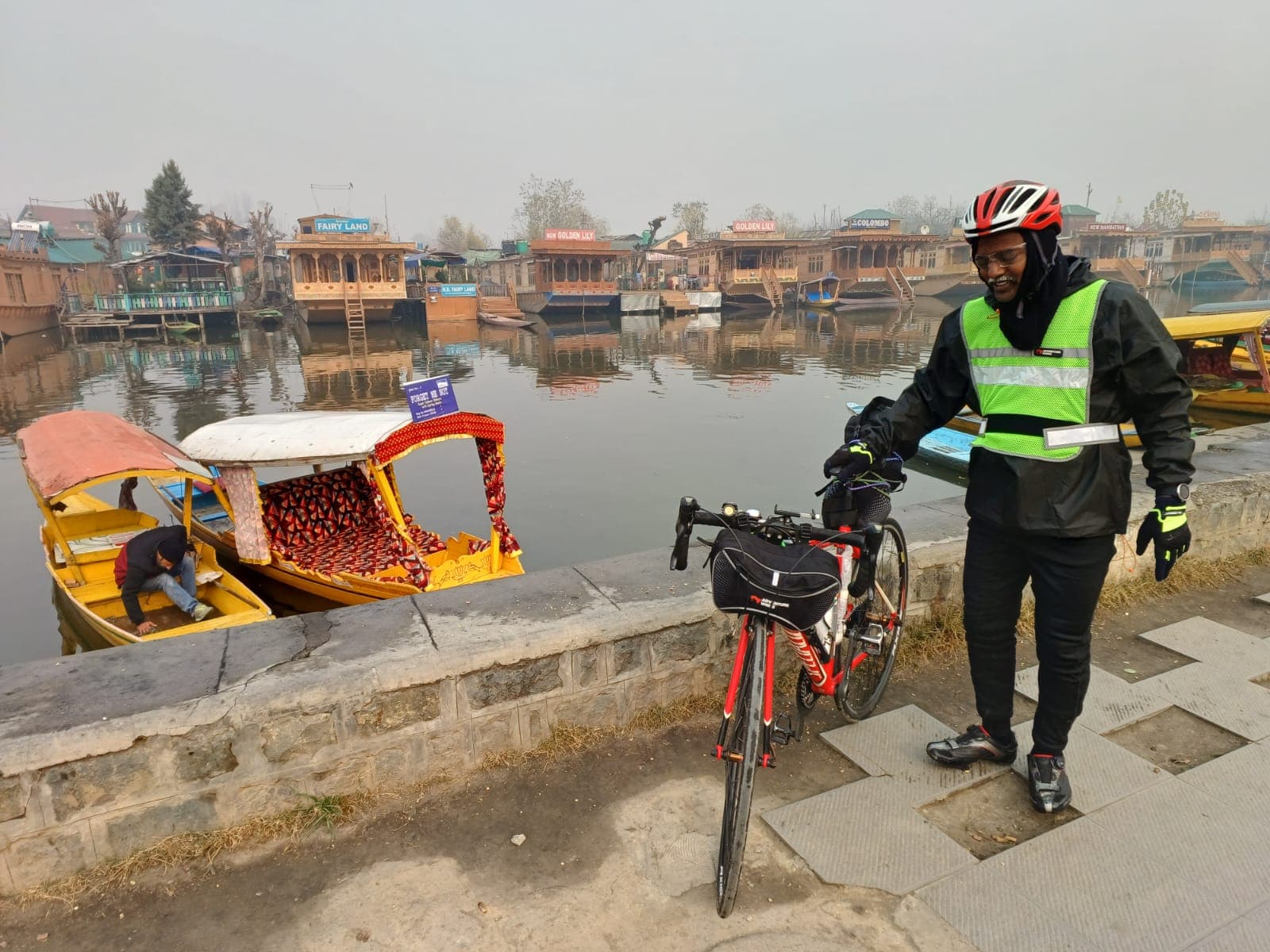 Bobba Ravinder Reddy with his bicycle beside the houseboats of Dal Lake, Srinagar