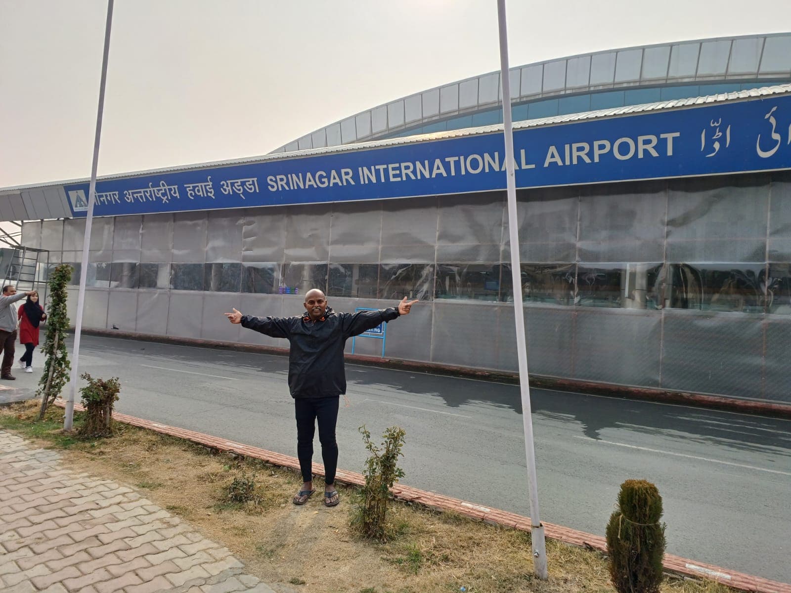 Bobba Ravinder Reddy posing with arms outstretched in front of Srinagar International Airport