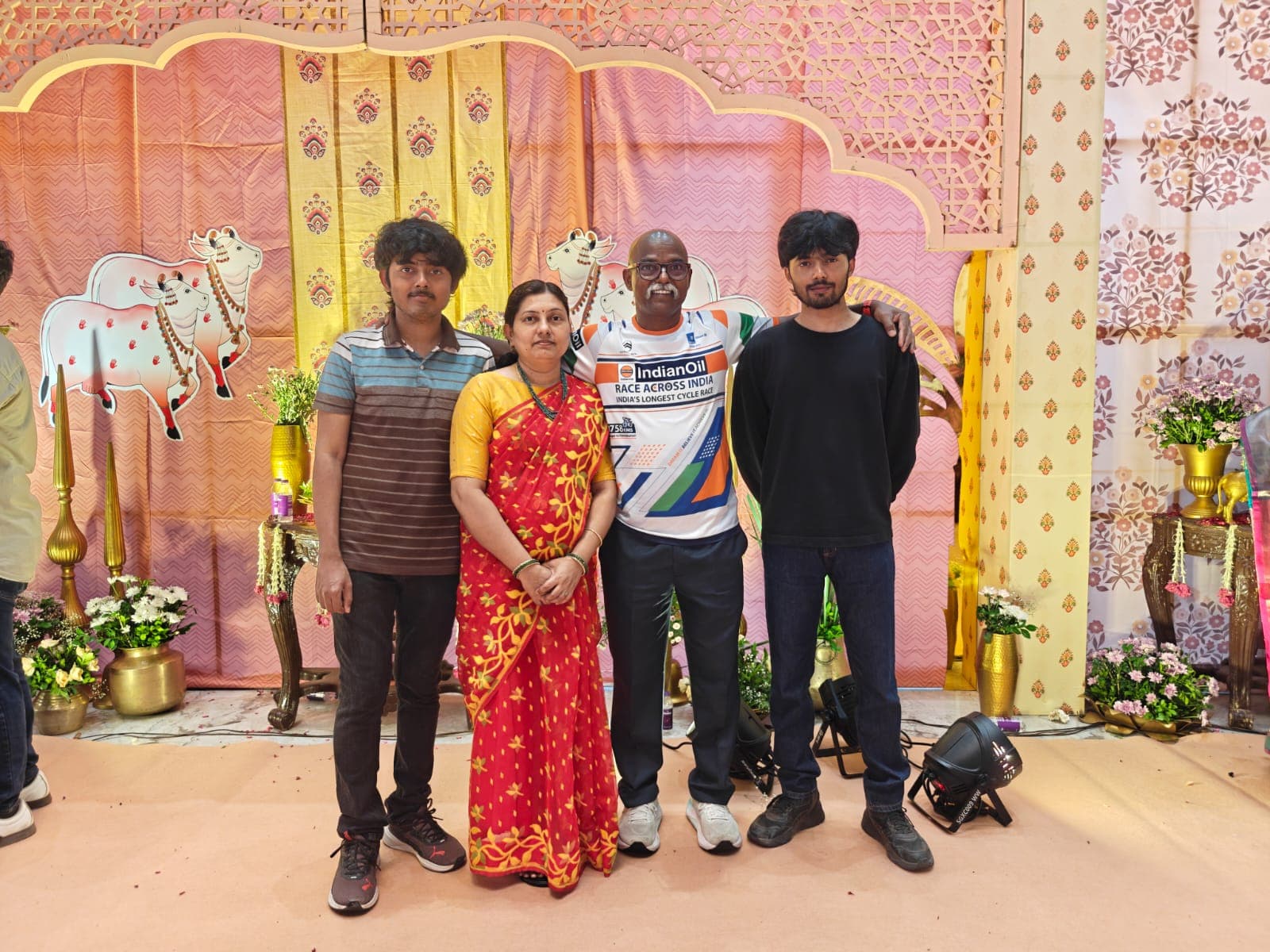 Family posing at a festive housewarming ceremony backdrop decorated with cow motifs and flowers