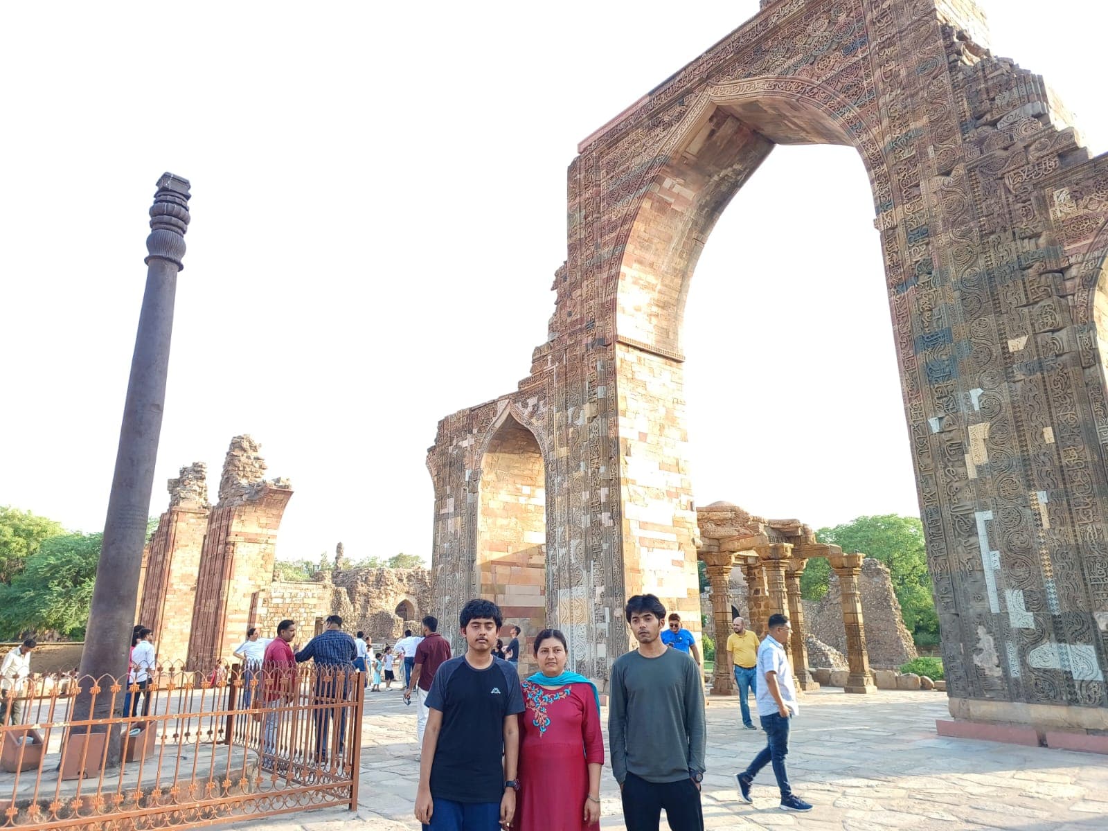 Two sons and their mother at the Qutub Minar complex beside the Iron Pillar of Delhi