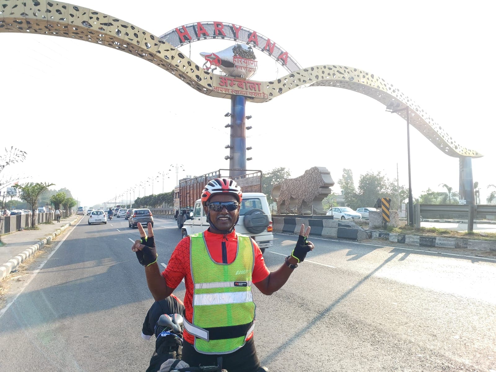 Bobba Ravinder Reddy giving peace signs beneath the Haryana Ambala welcome arch