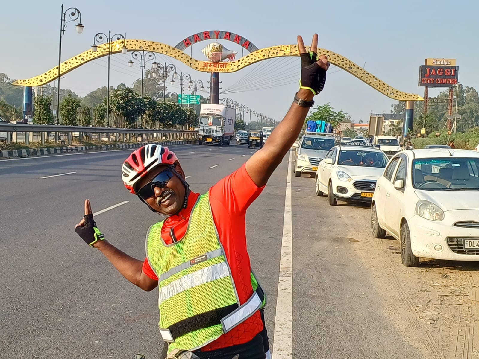 Bobba Ravinder Reddy cycling past the Haryana Ambala welcome arch with arm raised