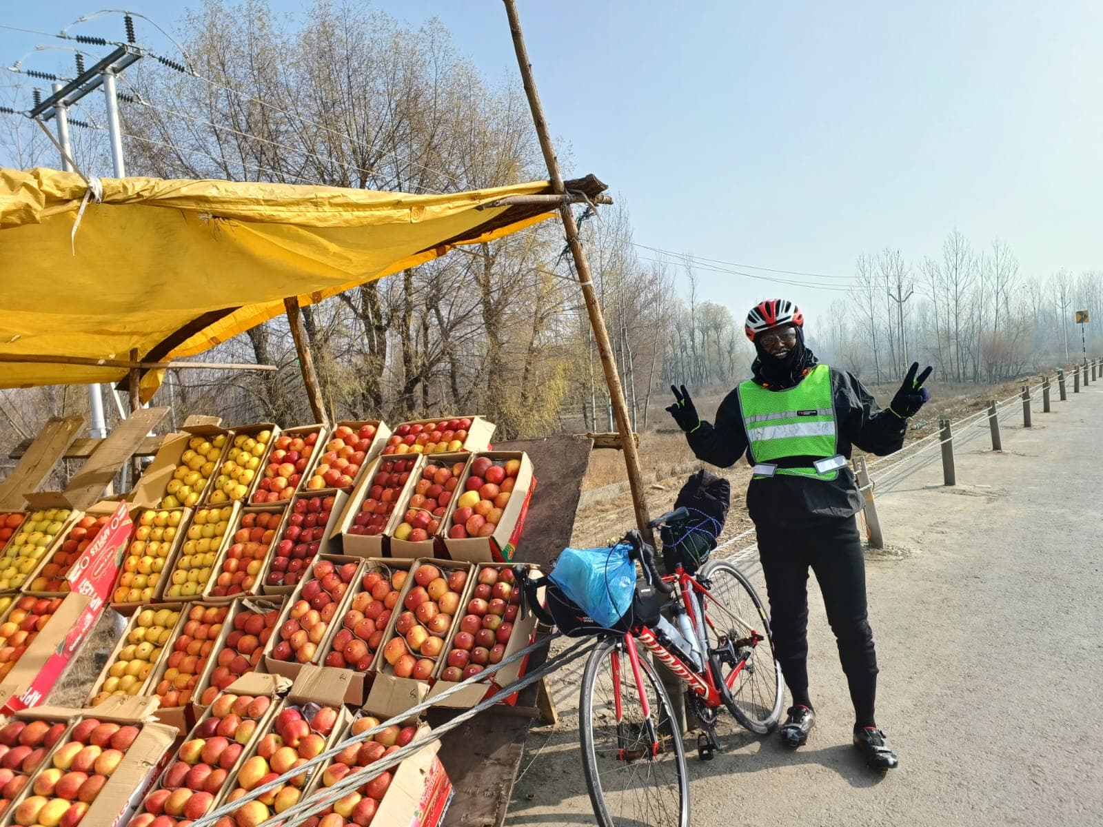 Bobba Ravinder Reddy pausing at a roadside apple stall during his Kashmir cycling journey