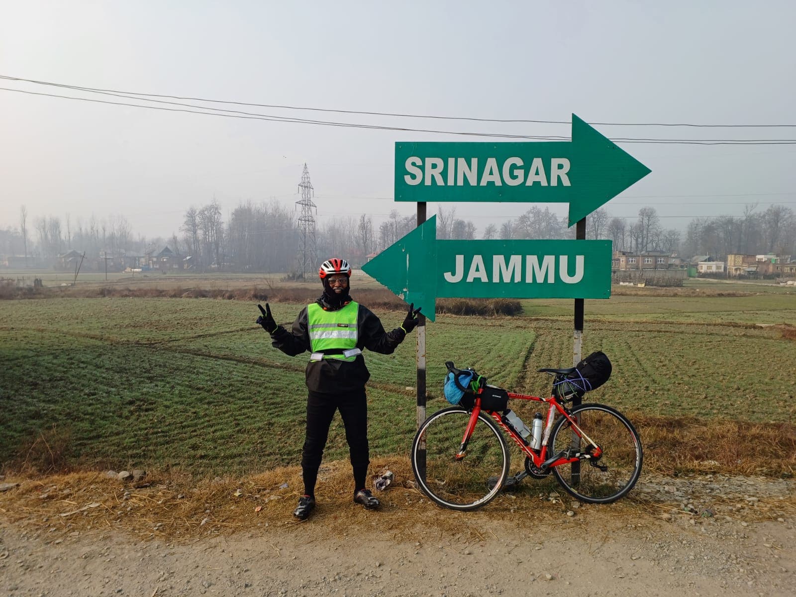 Bobba Ravinder Reddy posing with his bicycle at the Srinagar-Jammu road sign junction